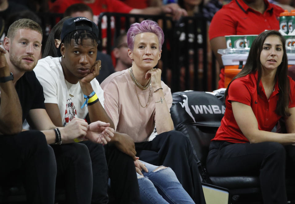 Soccer player Megan Rapinoe, center, watches during the first half of a WNBA All-Star game Saturday, July 27, 2019, in Las Vegas. (AP Photo/John Locher)