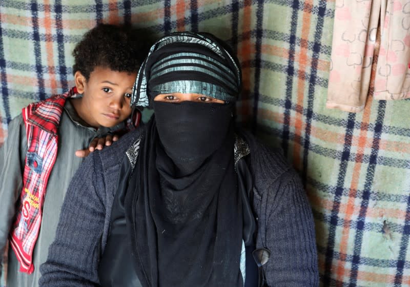 Sameera Hussein Nasser, 40, sits with one of her sons in a hut where they live at a camp for internally displaced people near Sanaa