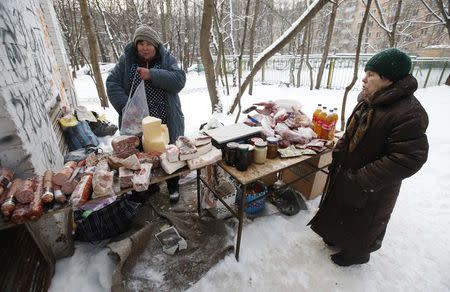 A woman stands near a counter as a street vendor sells food in a yard of an apartment building in Moscow, January 26, 2015. REUTERS/Maxim Zmeyev