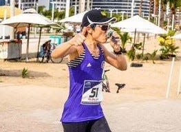 Detroit nurse anesthetist Jin Zhu of Farmington Hills gives a thumbs up as she quaffs an energy drink while nearing a marathon finish in Brazil on Feb. 6, 2023. By midnight, she was about to run another marathon in Miami, her last of seven on seven continents in a week.