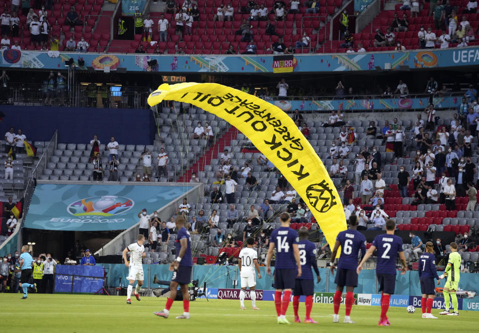 A Greenpeace paraglider lands on the pitch before the Euro 2020 soccer championship group F match between France and Germany at the Allianz Arena in Munich, Germany, Tuesday, June 15, 2021. (AP Photo/Matthias Schrader, Pool)