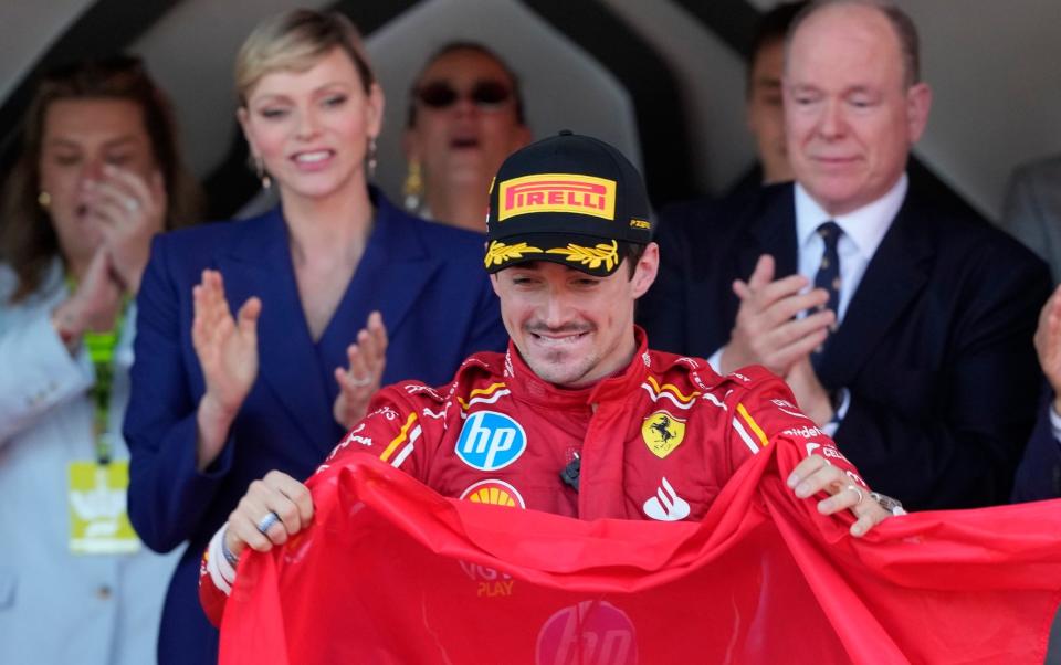 Charles Leclerc holds up the Monaco flag on the podium