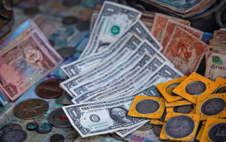 FILE PHOTO: U.S. dollar bills lie with old coins and currency notes at a money changer booth along a road in Karachi December 29, 2011. REUTERS/Akhtar Soomro/File Photo