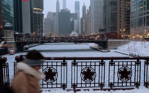 A pedestrian walks by Chicago River almost coated in ice - Credit: &nbsp;REUTERS