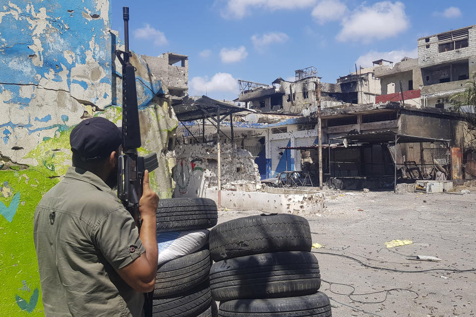 A member of Palestinian President Mahmoud Abbas' Fatah group stands guard in front of houses riddled with bullets after the deadly clashes between Palestinian factions in the Palestinian refugee camp of Ein el-Hilweh near the southern port city of Sidon, Lebanon, Thursday, Aug. 3, 2023. The caretaker Lebanese prime minister called the Palestinian president on Thursday to demand an end to the volatile situation in Lebanon's largest Palestinian refugee camp, warning that the army may have to intervene to stop the days-long fighting that has left dozens dead and wounded. (AP Photo/Mohammad Zaatari)