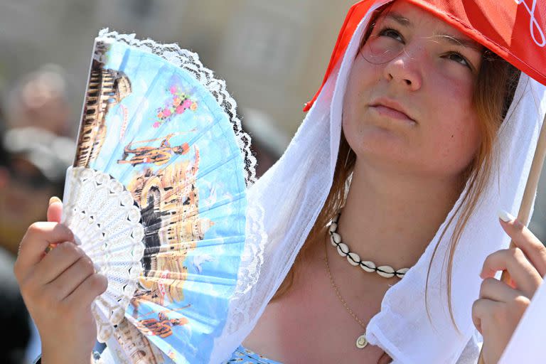 Una niña sostiene un abanico para refrescarse del calor mientras espera el Ángelus del Papa Francisco en el Vaticano el 9 de julio de 2023.