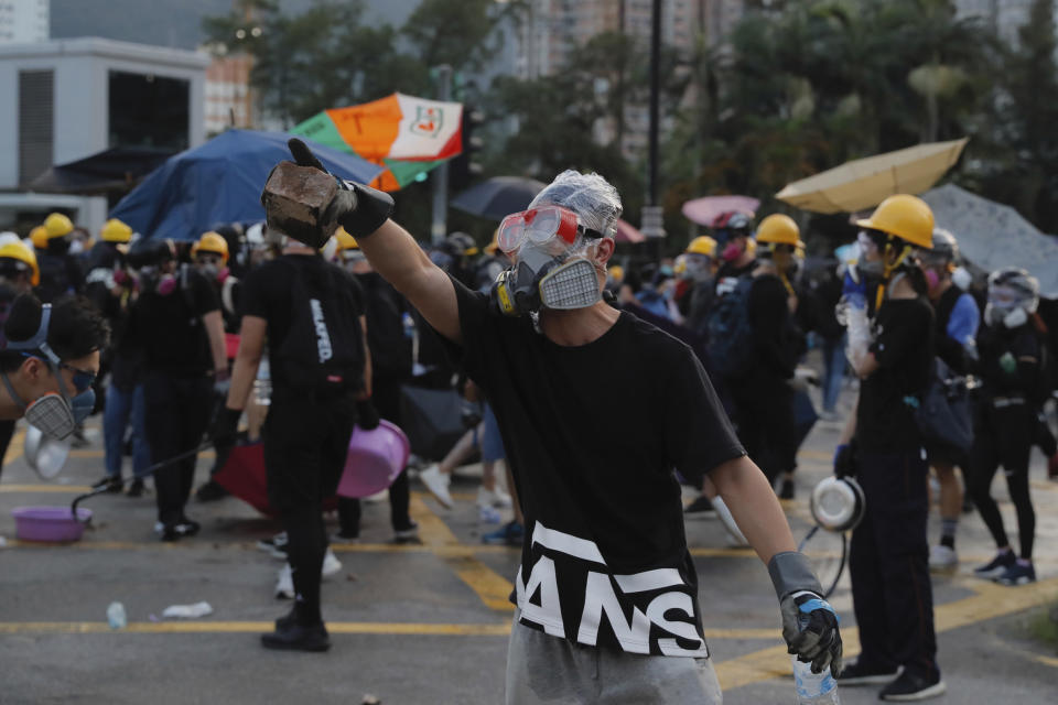 A protester holds a brick during confrontation with police in Hong Kong Monday, Aug. 5, 2019. Droves of protesters filled public parks and squares in several Hong Kong districts on Monday in a general strike staged on a weekday to draw more attention to their demands that the semi-autonomous Chinese city's leader resign.(AP Photo/Kin Cheung)