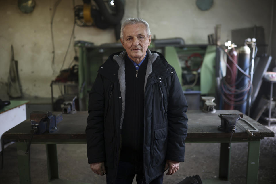 Wartime inventor, engineer and former teacher Aziz Lepenica, poses for a photo after an interview with Associated Press inside a high school workshop in Gorazde, Bosnia, Monday, Dec. 19, 2022. To survive and keep the lights on in their besieged town - cut off throughout Bosnia's 1992-95 interethnic war from access to electricity grid, food, medicine and the outside world - the people of Gorazde had to come up with various creative inventions. (AP Photo/Armin Durgut)