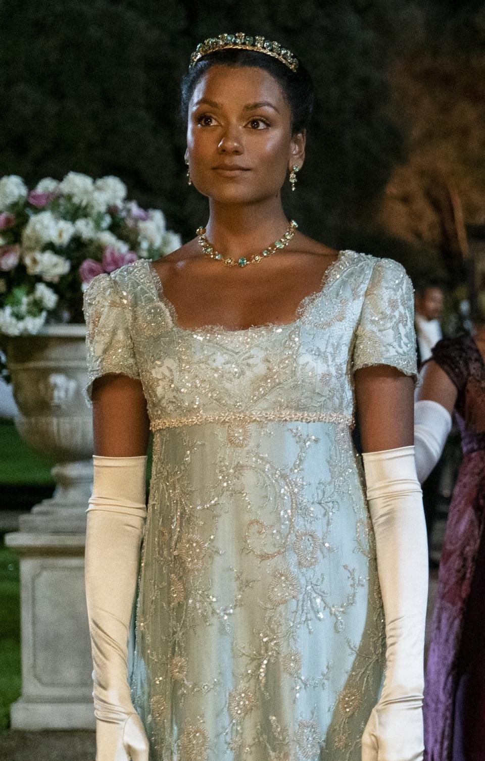 Simone Ashley in period costumes with gloves and sparkly details and tiara