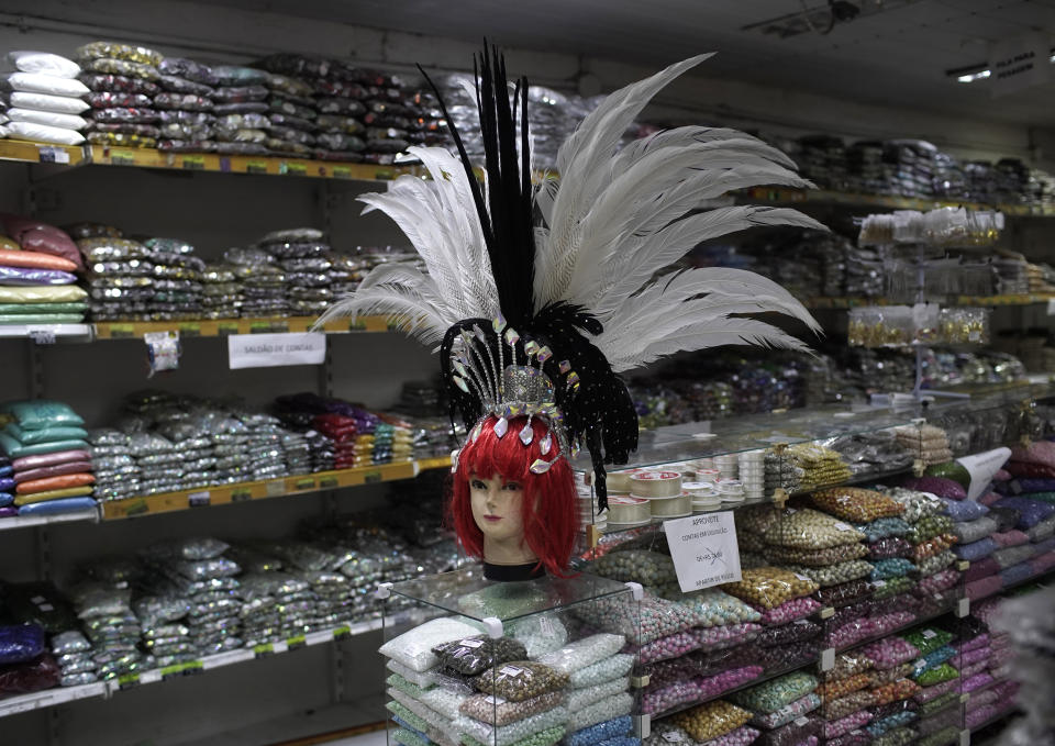 A mannequin head dons a Carnival feather headdress for sale at a costume party store in Rio de Janeiro, Brazil, Thursday, Feb. 4, 2021, amid the COVID-19 pandemic. The cancellation of Carnival celebrations due to the new coronavirus pandemic has created a deep economic hole for many businesses dependent on the massive crowds attracted to the annual street party. (AP Photo/Silvia Izquierdo)