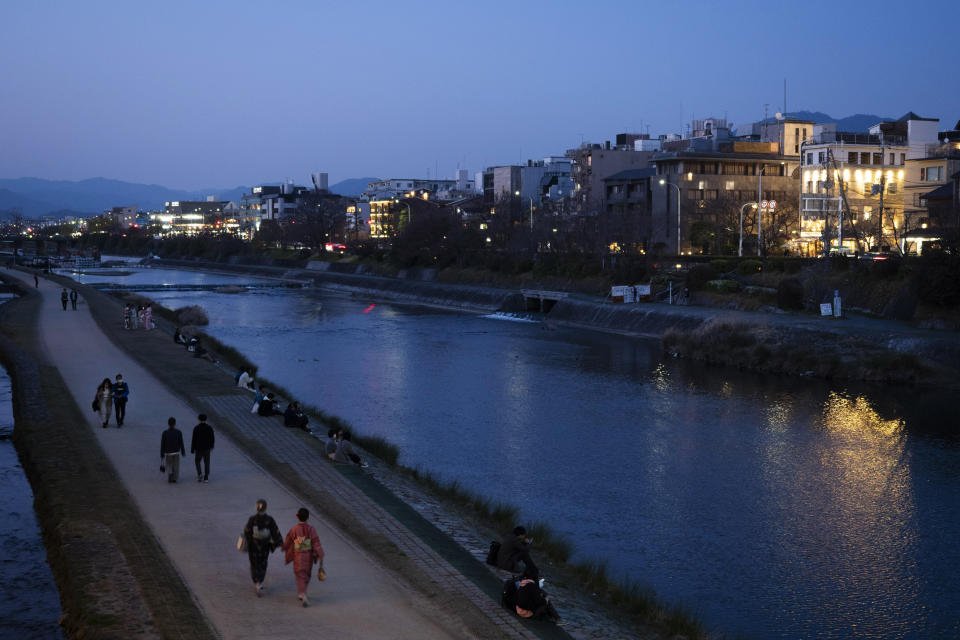 People stroll along the Kamo River in Kyoto, Japan, March 18, 2020. Kyoto's city government has an emergency fund for small to medium-size businesses who suffered sharp sales decline since the coronavirus outbreak. (AP Photo/Jae C. Hong)