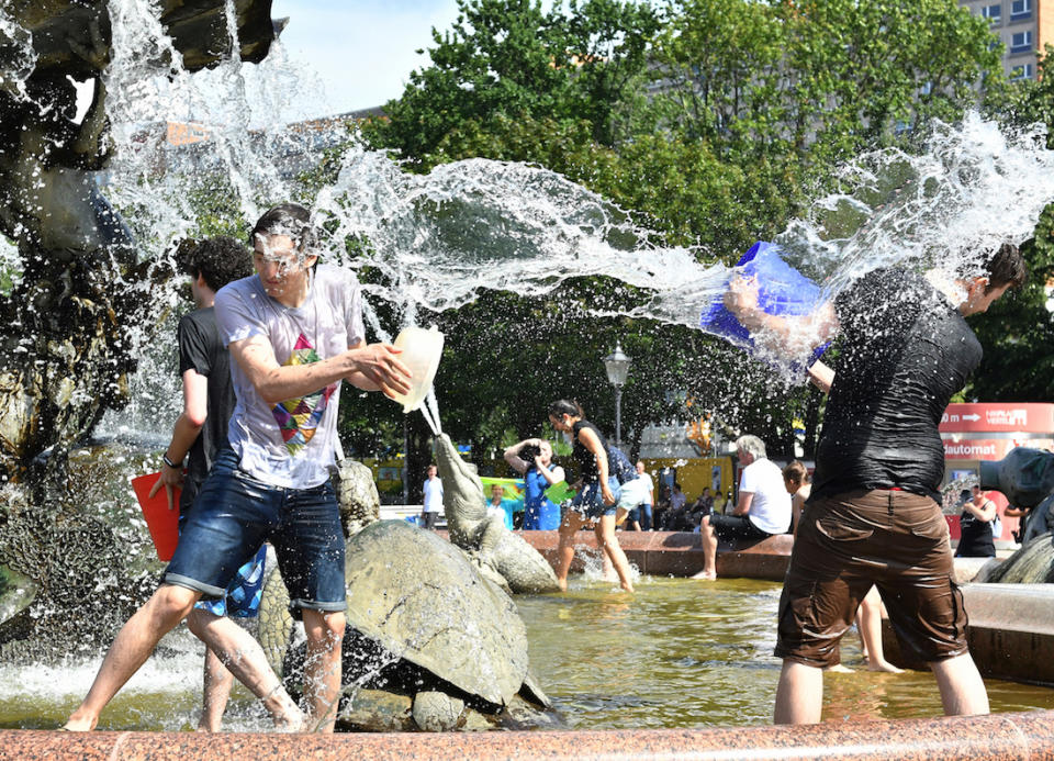 <p>Berliner vergnügen sich während tropischer Temperaturen mit einer Wasserschlacht am Neptunbrunnen. (Bild: Paul Zinken/dpa) </p>