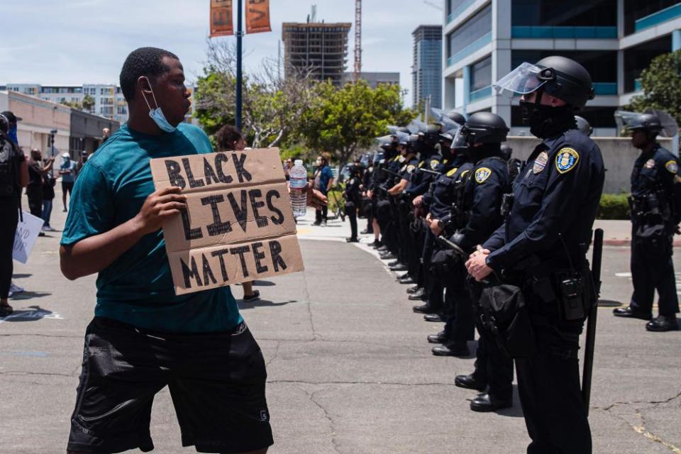 A man holds a Black Lives Matter sign in front of a line of San Diego police officers on 31 May 2020.