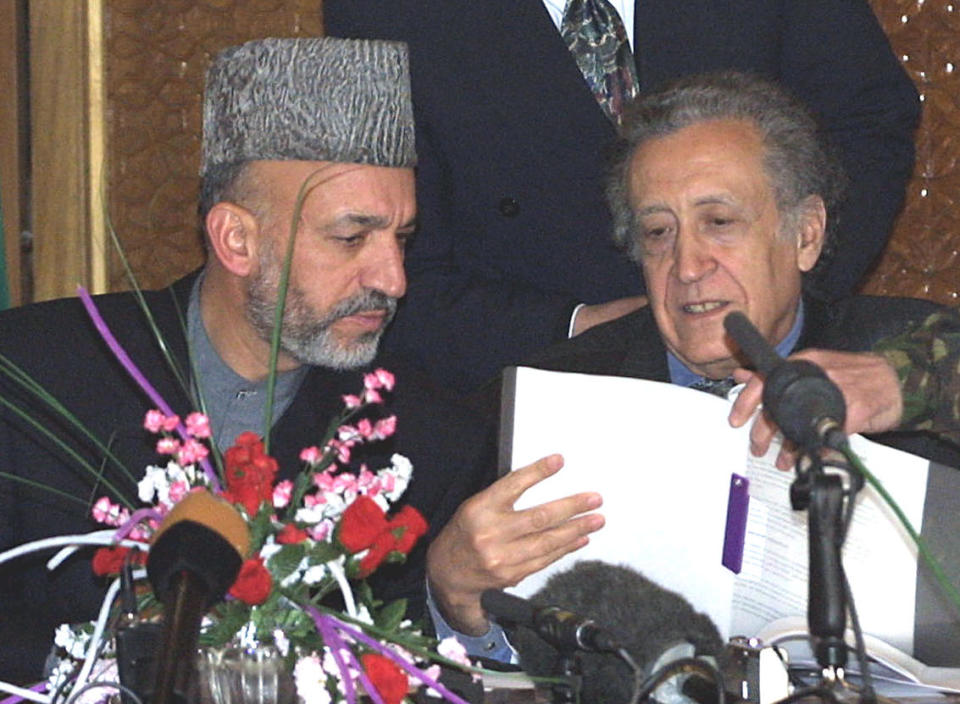 FILE - This is a Friday, Jan. 4, 2002 file photo of Afghan interim Prime Minister Hamid Karzai, left, and U.N. Special Representative to Afghanistan Lakhdar Brahimi, examine the agreement which establishes the role of International Security Assistance Force for Afghanistan, at a gathering in Kabul. Lakhdar Brahimi has seen faces like these before, barely able to remain in the same room, much less speak to each other. Lebanese, Afghans, Iraqis, now Syrians. Even, two decades ago, Algerians like himself. For days now, the veteran U.N. mediator has presided over peace talks intended to lead the way out of Syria's civil war. He brought President Bashar Assad's government and the opposition face to face for the first time on Saturday, Jan. 25, 2014, while still ensuring that they don't have to enter by the same door or address each other directly. He is 80. He is patient. (AP Photo/Brennan Linsley. File)