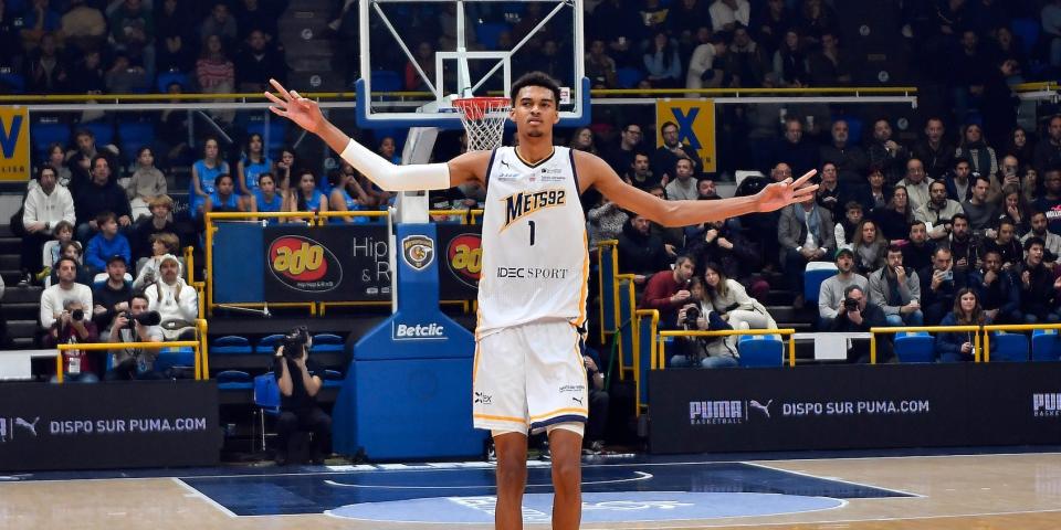 Victor Wembanyama holds out his arms in celebration during a basketball game.