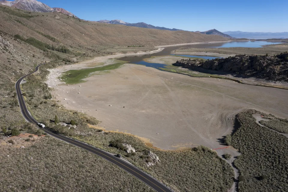 An aerial view of a vast expanse of bare lake, showing a road that used to hug the waterline.