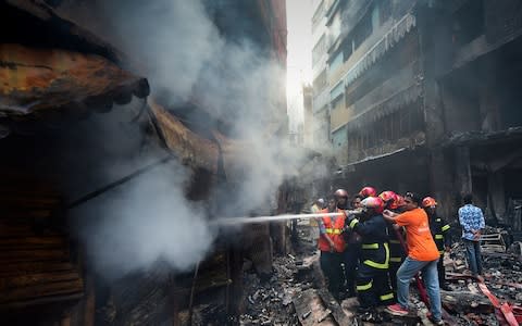 Firefighters try to extinguish a fire in Dhaka - Credit: AFP