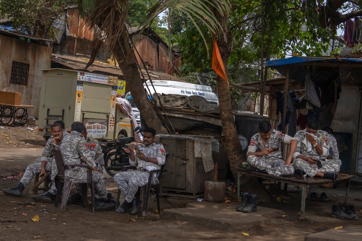 Soldiers sit under the shade of a tree outside a vote-counting centre in Mumbai on Monday (AP)