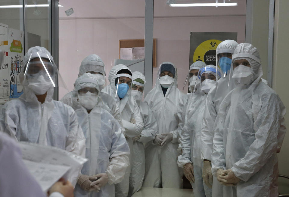 FILE - In this Friday, May 15, 2020, file photo, a team of Turkey's Health Ministry's coronavirus contact tracing team, clad in white protective gear, masks and face shields are briefed in Istanbul. When Turkey changed the way it reports daily COVID-19 infections, it confirmed what medical groups and opposition parties have long suspected — that the country is faced with an alarming surge of cases that is fast exhausting the Turkish health system. The official daily COVID-19 deaths have also steadily risen to record numbers in a reversal of fortune for the country that had been praised for managing to keep fatalities low. With the new data, the country jumped from being one of the least-affected countries in Europe to one of the worst-hit.(AP Photo/Emrah Gurel, File)