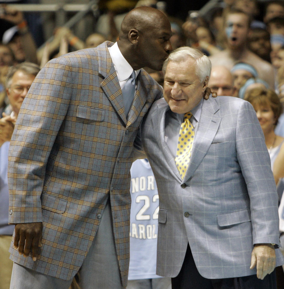 FILE - Former North Carolina player Michael Jordan, left, gives his former coach Dean Smith a kiss during halftime of a college basketball game between North Carolina and Wake Forest in Chapel Hill, N.C., Saturday, Feb. 10, 2007. (AP Photo/Gerry Broome)