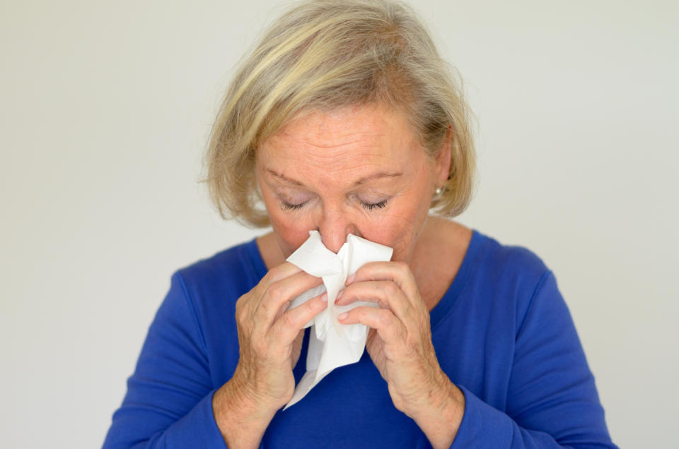 an elderly woman blowing her nose