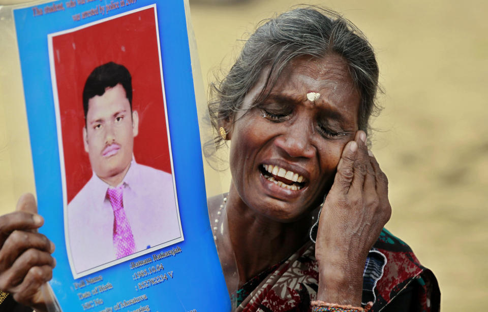 In this Friday, Nov. 15, 2013, file photo, a Sri Lankan ethnic Tamil woman cries holding a portrait of her missing son during a protest in Jaffna, Sri Lanka. Sri Lanka's president has decided that tens of thousands of people still missing from the country's quarter-century civil war will be formally declared dead and death certificates will be issued, his office said Monday. (AP Photo/Eranga Jayawardena)