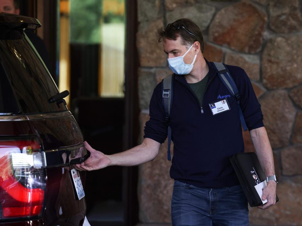 Chris Urmson lifts car tailgate while wearing face mask