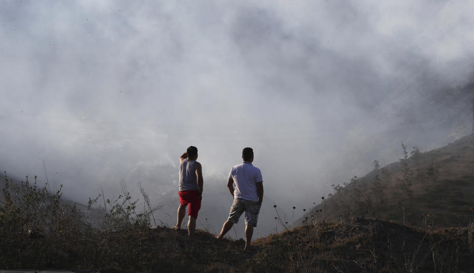 Hombres observan un area de incendio en el cerro Casitagua al norte de Quito, Ecuador, el miércoles 15 de enero de 2020. (AP Fotos/Dolores Ochoa)