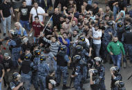 FILE - In this Tuesday, Oct. 29, 2019 file photo, riot police try to stop supporters of the Shiite Hezbollah group who arrived to burn and destroy tents in the camp set up by anti-government protesters near the government palace, in Beirut, Lebanon. Young protesters face the challenges of a political leadership that depends on sectarianism and an older generation that fears disrupting it could bring back civil war.(AP Photo/Hussein Malla, File)