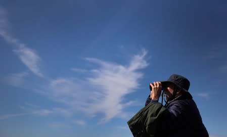 A member of the Cloud Appreciation Society looks through binoculars during a boat trip around Lundy