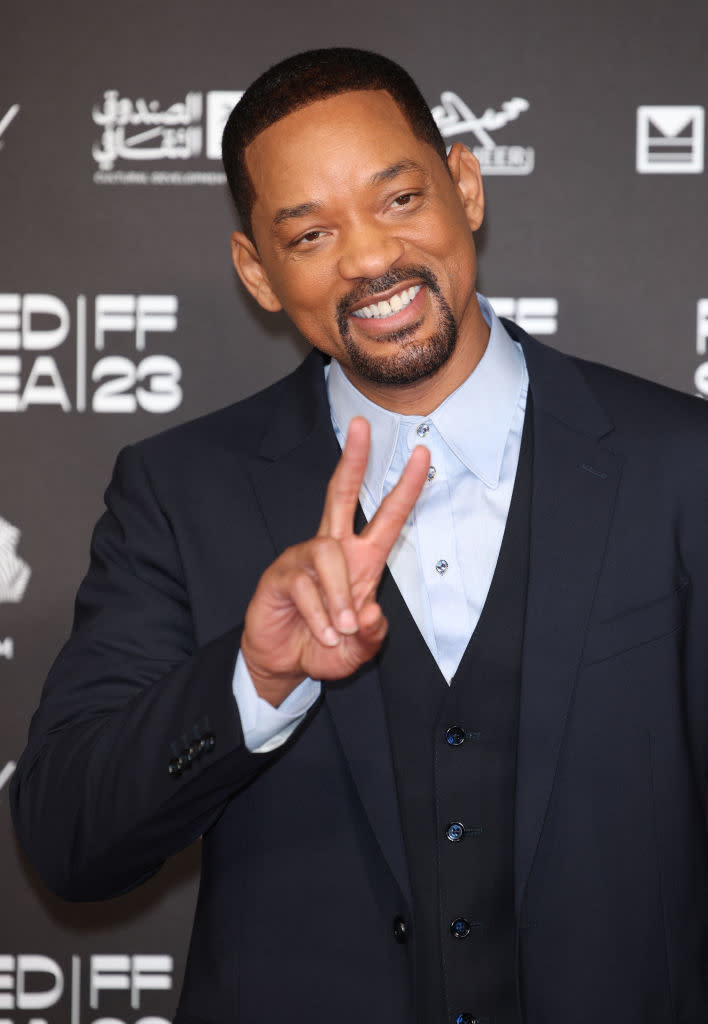 Will making a peace sign gesture at an event wearing a suit and he's got a goatee