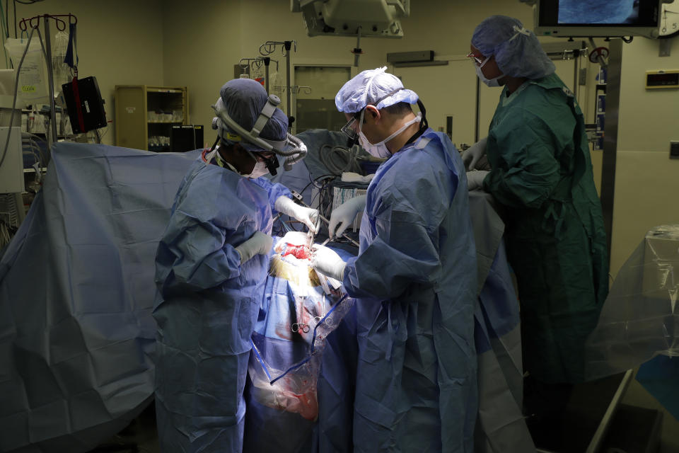 In this Jan. 14, 2020 photo, senior resident Dr. Ariana Barkley, left, assists neurosurgeon Dr. Andrew Ko, center, of the University of Washington School of Medicine, as surgical technician Melodie White, right, looks on as Genette Hofmann undergoes brain surgery at Harborview Medical Center in Seattle in hopes of reducing the epileptic seizures that had disrupted her life for decades. At the same time, Hofmann agreed to donate a small bit of her healthy brain tissue to researchers, who were eager to study brain cells while they were still alive, joining a long line of epilepsy patients who've helped scientists reveal basic secrets of the brain. (AP Photo/Ted S. Warren)