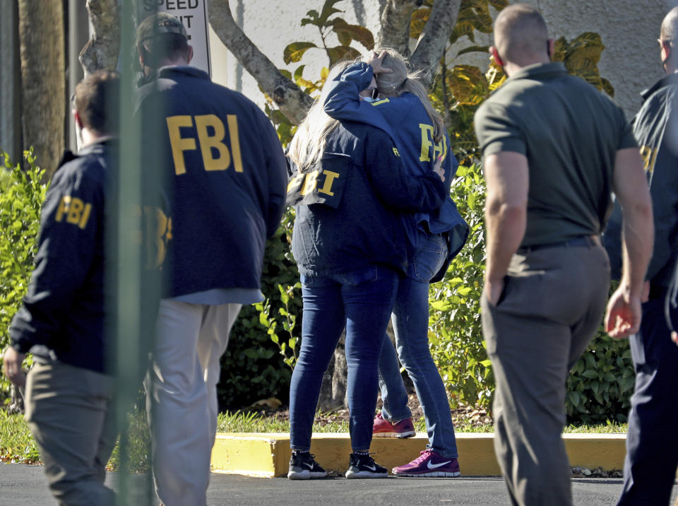 FBI agents console each other as they arrive at the Broward County Medical Examiner's Office in Dania, Fla., after two FBI agents were killed and three wounded while trying to serve a search warrant in Broward County on Tuesday Feb. 2, 2021. (Susan Stocker/South Florida Sun-Sentinel via AP)