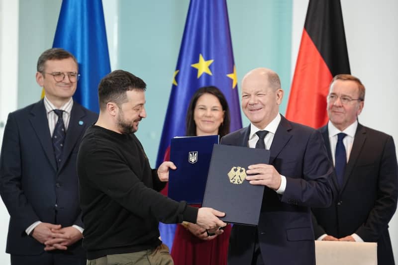 German Chancellor Olaf Scholz (2nd R) and Ukrainian President Volodymyr Zelensky, sign a long-term security agreement between the two countries at the Federal Chancellery. Kay Nietfeld/dpa