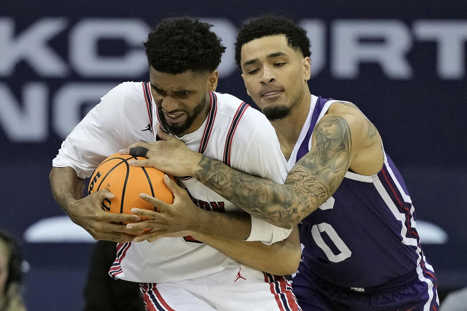 TCU guard Micah Peavy (0) tries to steal the ball from Houston guard Mylik Wilson (8) during the second half of an NCAA college basketball game in the quarterfinal round of the Big 12 Conference tournament, Thursday, March 14, 2024, in Kansas City, Mo. Houston won 60-45. (AP Photo/Charlie Riedel)