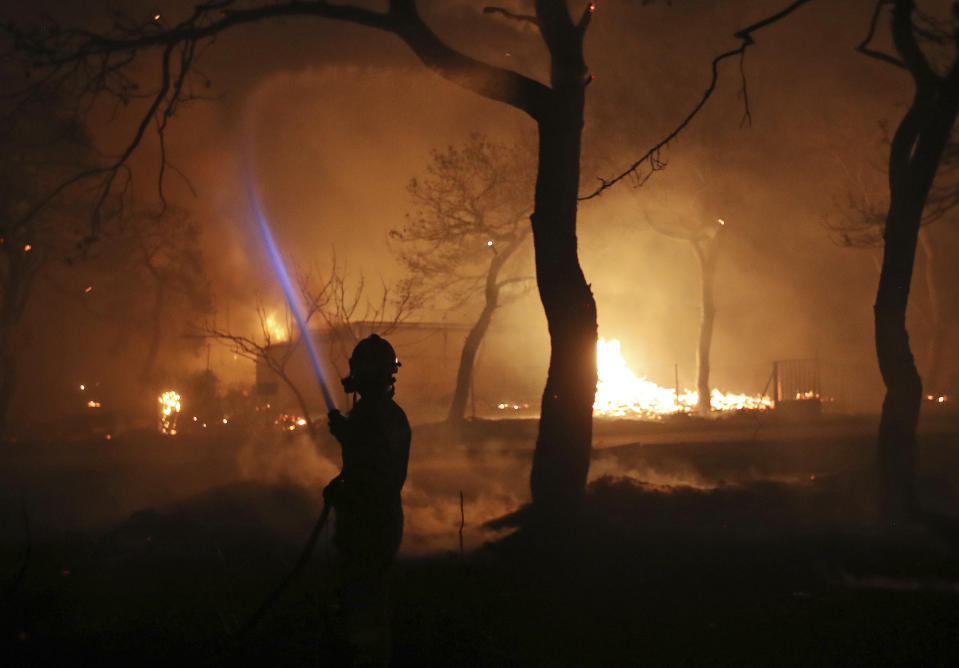 A firefighter sprays water on the fire in the town of Mati, east of Athens, Monday, July 23, 2018. Regional authorities have declared a state of emergency in the eastern and western parts of the greater Athens area as fires fanned by gale-force winds raged through pine forests and seaside settlements on either side of the Greek capital. (AP Photo/Thanassis Stavrakis)