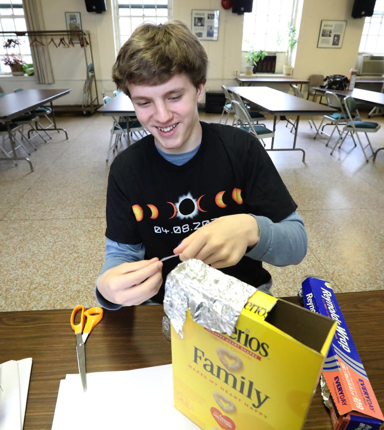 George Melis, a sophomore at Clarkstown South, shows the items needed to build a cereal box eclipse viewer at Cornell Cooperative Extension in Stony Point April 2, 2024. Step 5 - Wrap a piece of aluminum foil over one of the openings and tape it in place.