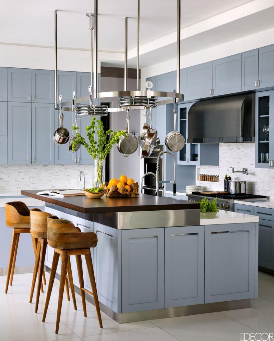 <p>A classic backsplash made of Carrara marble tiles by Walker Zanger adds balance to a powder blue kitchen in a Pacific Palisades, California, home belonging to designer Alison Palevsky and her husband, Alexander. The wooden bar stools are from Organic Modernism, the kitchen stove is by Viking, and the 1920s pendants are from Thanks for the Memories.<br></p>