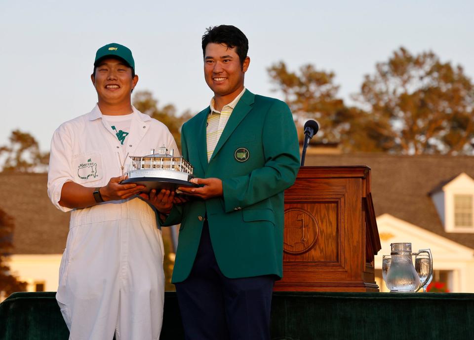 Hideki Matsuyama and his caddie Shota Hayafuji hold the Masters Tournament trophy in 2021at Augusta National Golf Club, Sunday, April, 11, 2021.