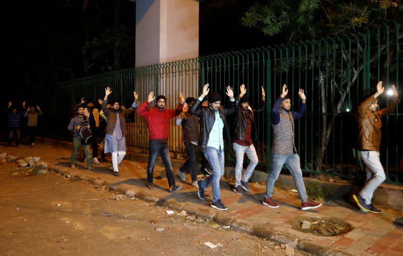 Students raising their hands leave the Jamia Milia University following a protest against a new citizenship law, in New Delhi