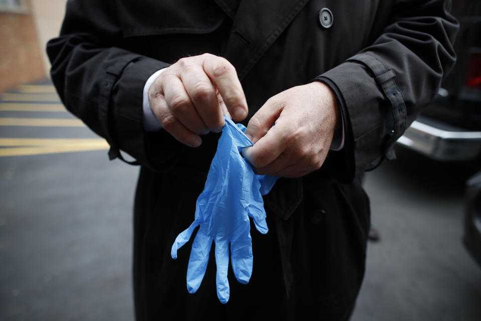 Funeral director Tom Cheeseman puts on protective gloves due to COVID-19 concerns as he delivers a body to a funeral home, Friday, April 3, 2020, in the Brooklyn borough of New York. “We took a sworn oath to protect the dead, this is what we do,” he said. “We’re the last responders. Our job is just as important as the first responders." (AP Photo/John Minchillo)
