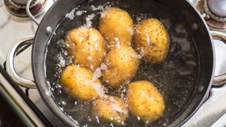 Whole potatoes boiling in pot on stove