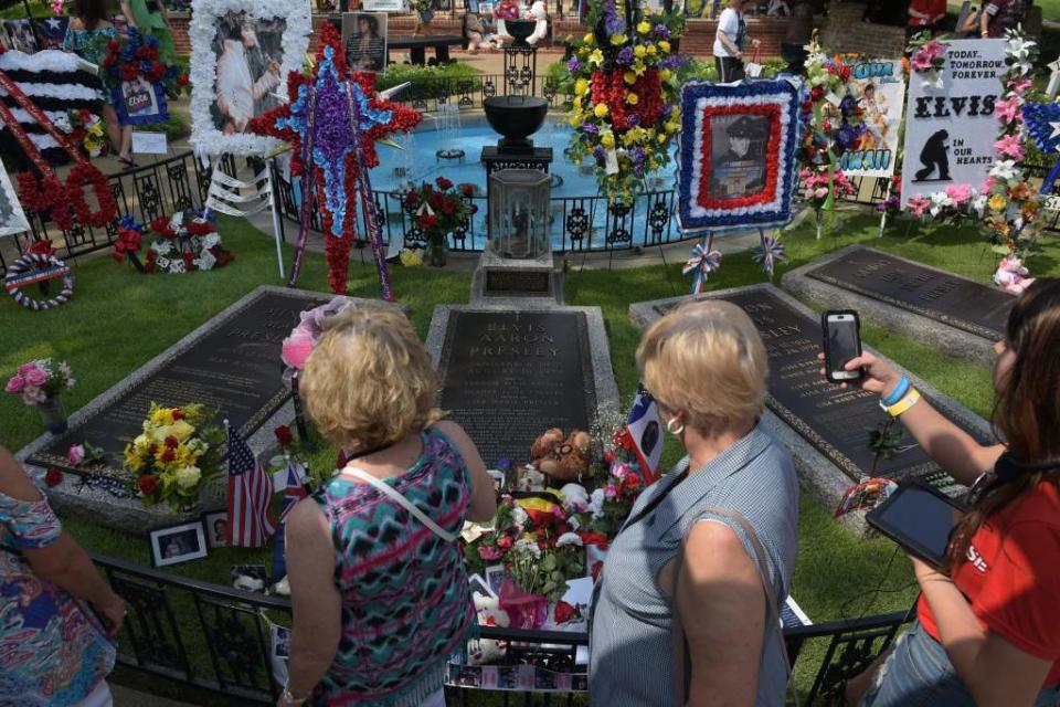 Fans file past the graves of Elvis Presley in the Meditation Garden where he is buried alongside his parents and grandmother at his Graceland mansion on Aug. 12, 2017 in Memphis, Tennessee. AFP via Getty Images