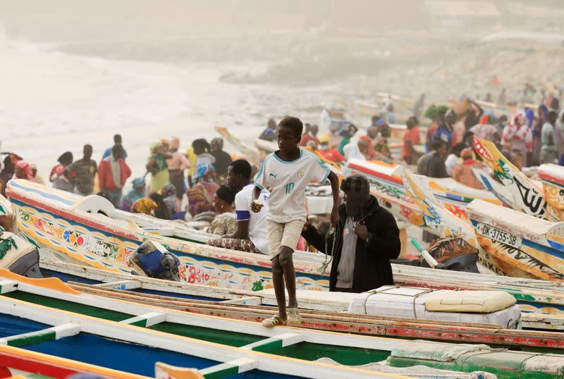 A boy jumps over pirogues as dust carried by winds from the Sahara Desert shrouds Dakar