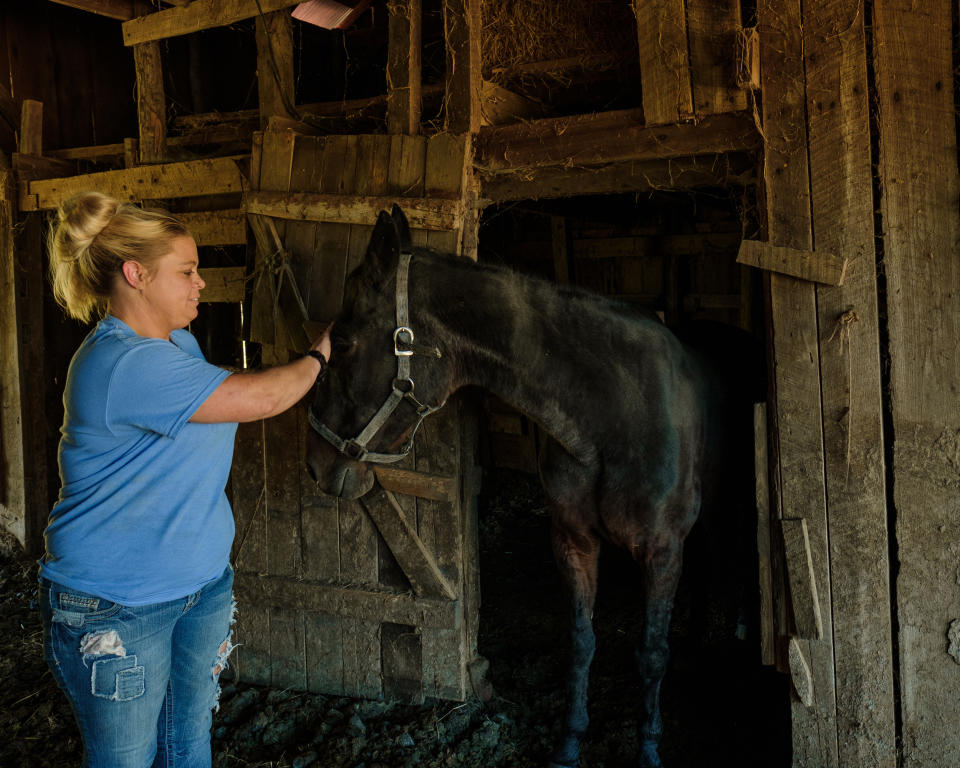 Snodgrass petting a black horse. (Stephanie Mei-Ling for NBC News and ProPublica)