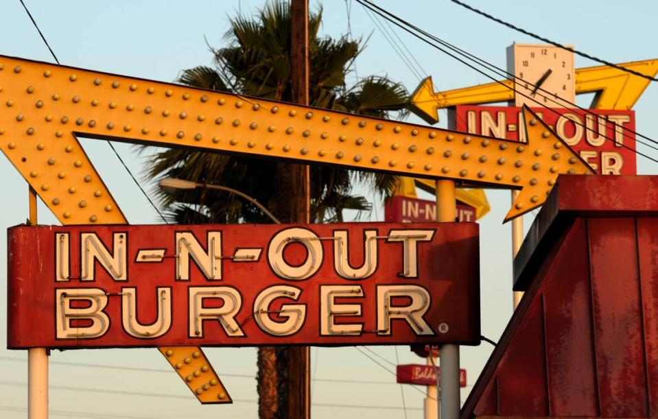 In-N-Out Burger signs, two in the foreground from the fast food chain’s original location, and one in the background at a new location in Baldwin Park, Calif.