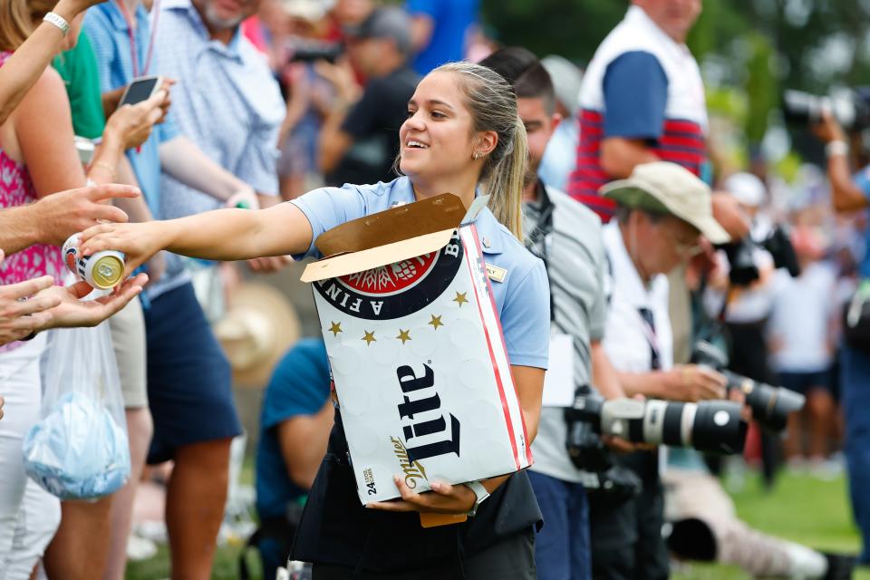 BEDMINSTER, NJ - JULY 31:  A women hands out beer to fans at the 16th tee during the 3rd round of the LIV Golf Invitational Series Bedminster on July 31, 2022 at Trump National Golf Club in Bedminster, New Jersey. (Photo by Rich Graessle/Icon Sportswire via Getty Images)