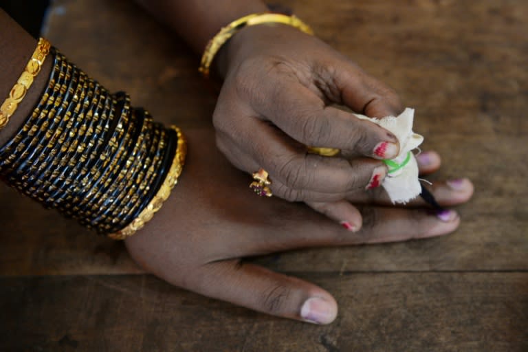 An election official puts indeliable ink on the finger of a voter before she casts her ballot