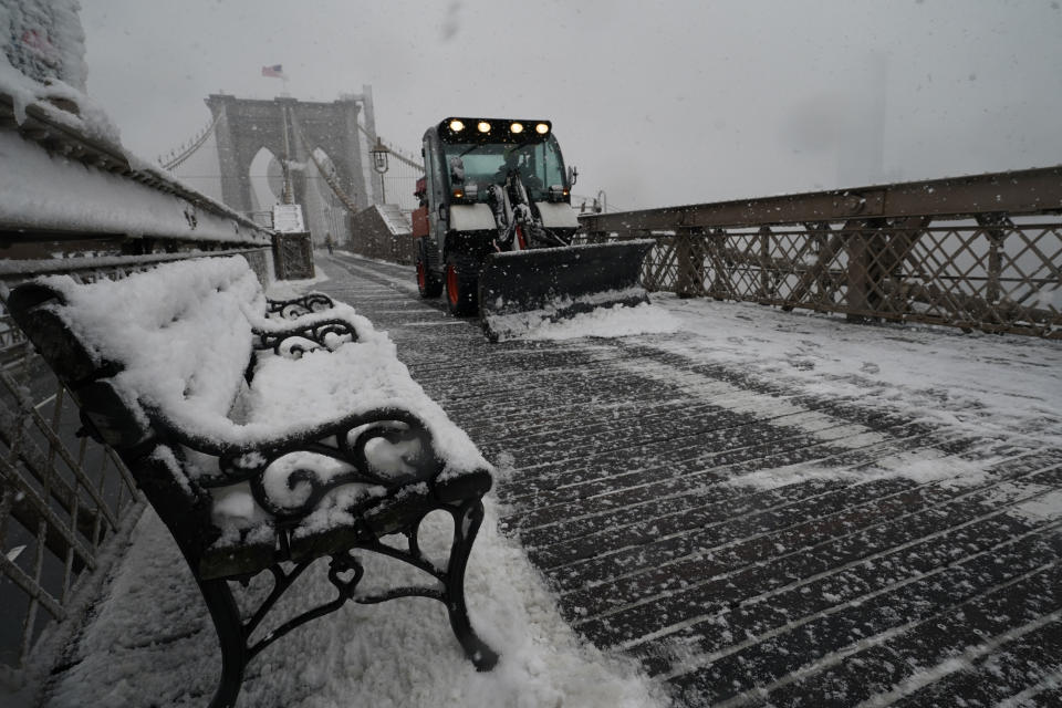 A snowplow makes it's way across the pedestrian walkway of the Brooklyn Bridge during a snowstorm, Sunday, Feb. 7, 2021, in New York. It was the second major snowstorm in less than week to hit the area. (AP Photo/Kathy Willens)