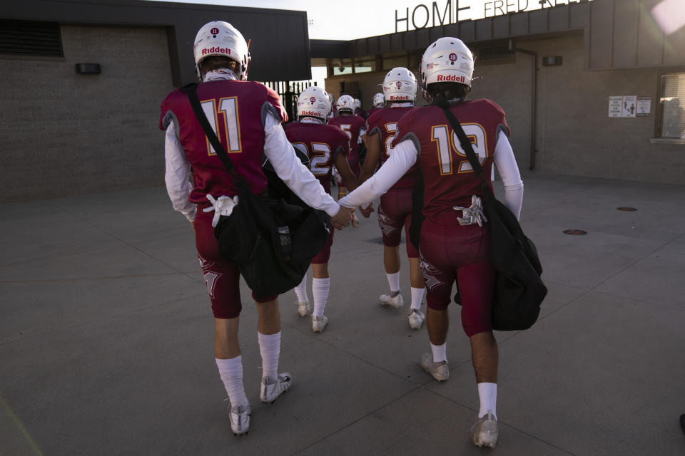 El Modena players hold hands as they walk into a stadium for the team's high school football game with El Dorado in Orange, Calif., Friday, March 19, 2021. (AP Photo/Jae C. Hong)